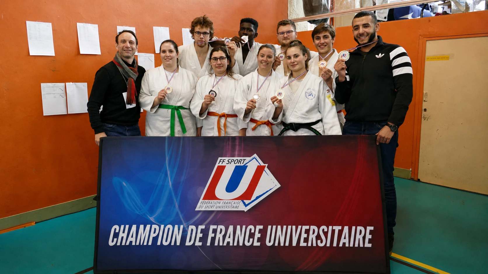 Équipe universitaire de judo réunie derrière la bannière Champion de France universitaire
