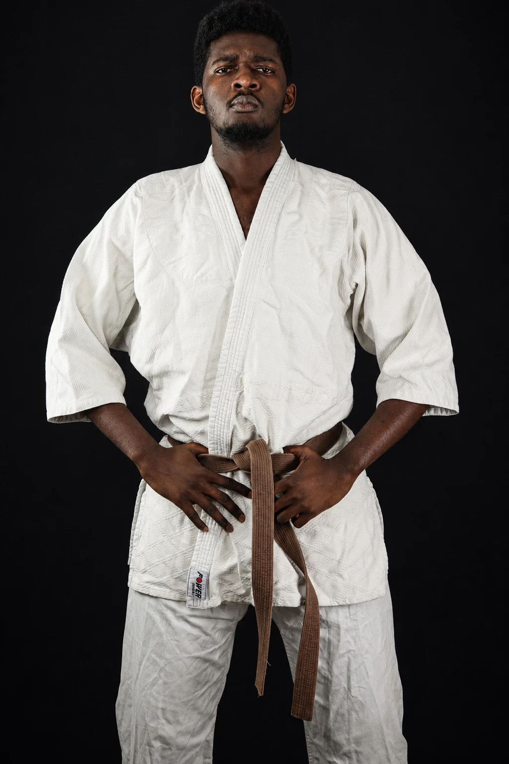 Portrait en judogi, ceinture marron, sur fond noir
