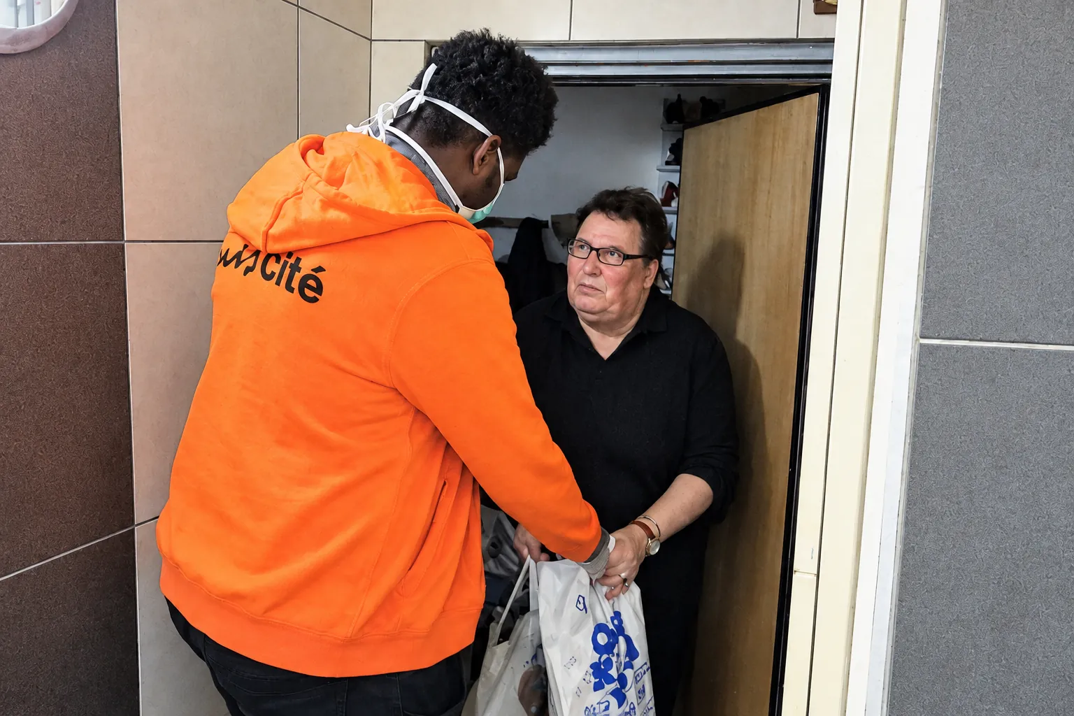 Giovani remet un sac de provisions à une personne âgée à Reims durant le confinement